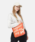 Person holding a colorful bag with text happiest with my dog and a chihuahua dog illustration. The tote bag has striped pink and orange background 
